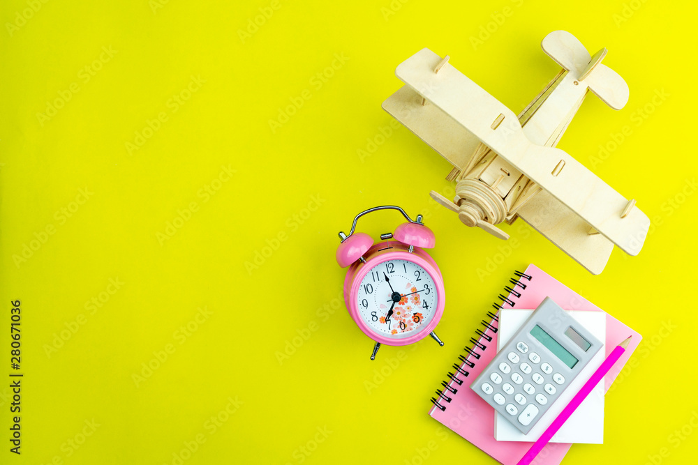 New alarm clock with wood Airplane,business white paper note,calculator and pencil on yellow paper b