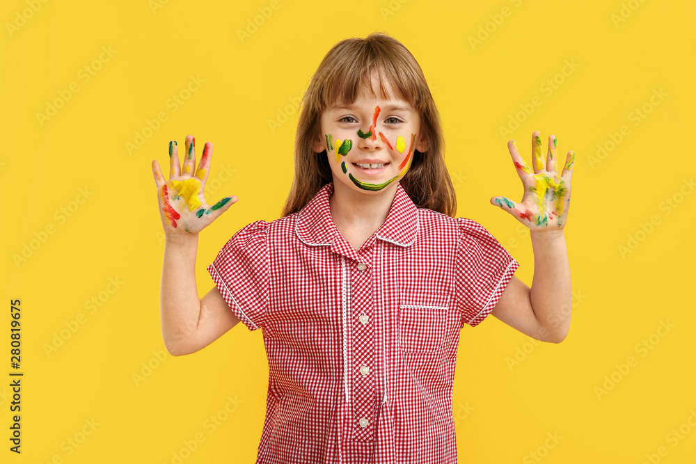 Funny little girl with hands and face in paint on color background