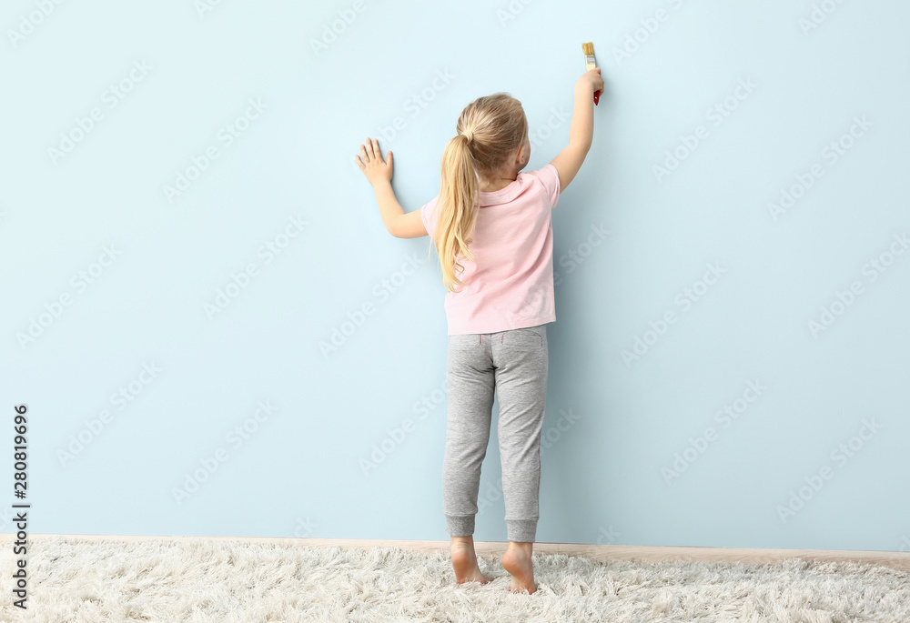 Little girl painting on color wall