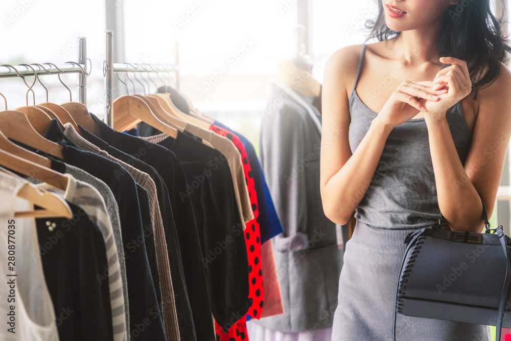 Beautiful woman shopping for clothes at retail apparel shop in the shopping mall. Modern trade lifes