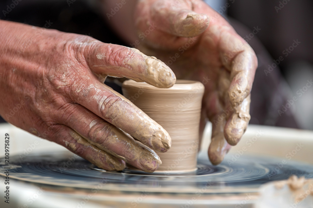 Potter makes pottery dishes on potters wheel