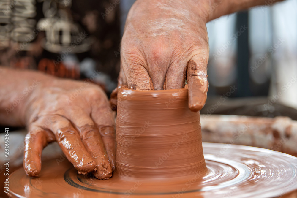 Potter makes pottery dishes on potters wheel