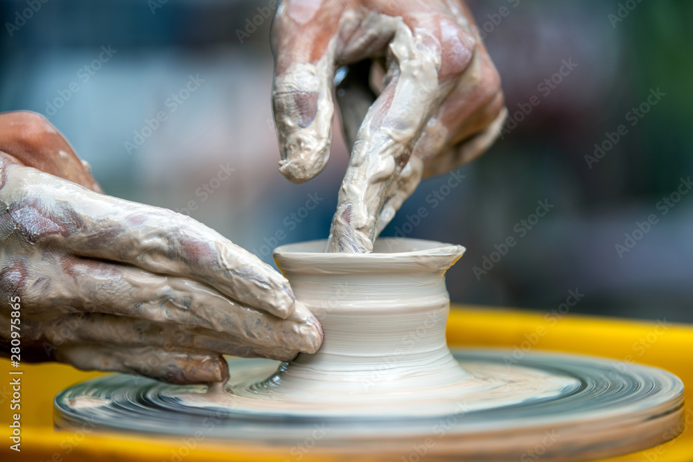 Potter makes pottery dishes on potters wheel