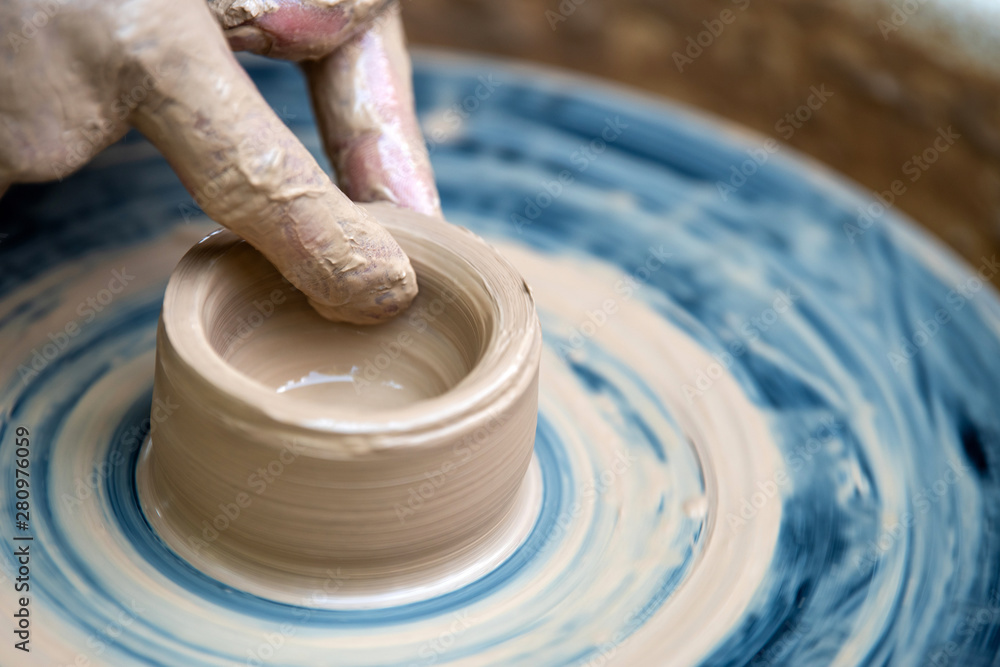 Potter makes pottery dishes on potters wheel