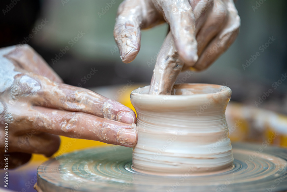 Potter makes pottery dishes on potters wheel