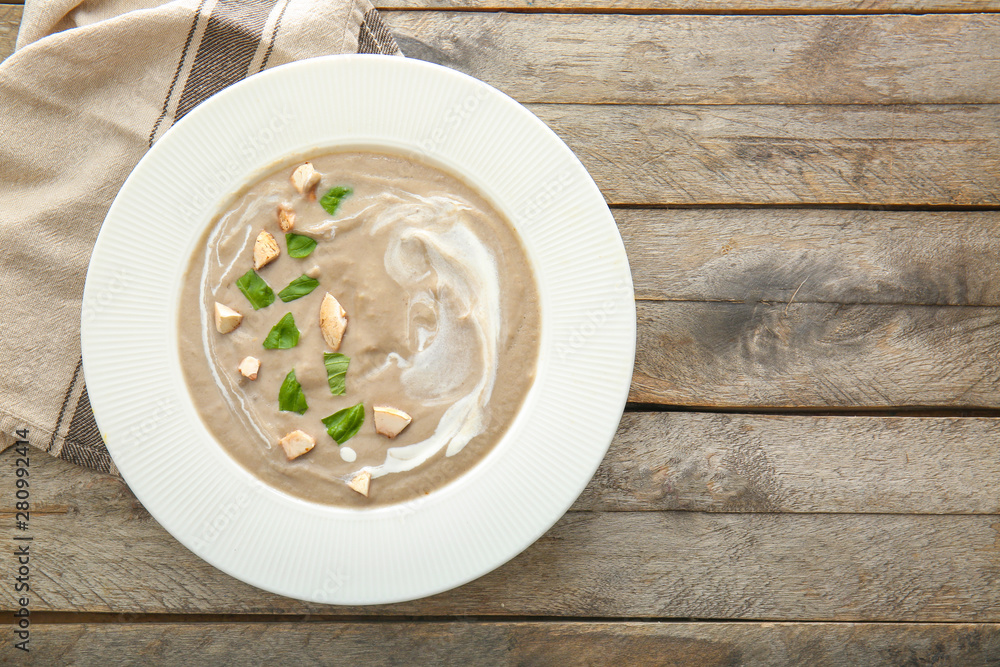 Plate of tasty mushroom cream soup on wooden table