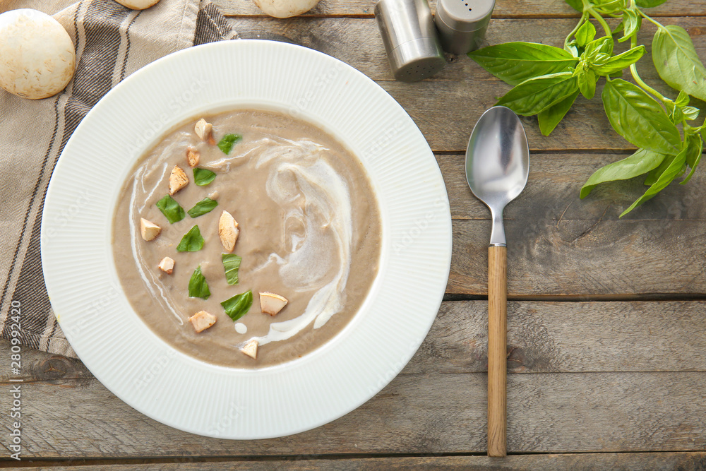 Plate of tasty mushroom cream soup on wooden table