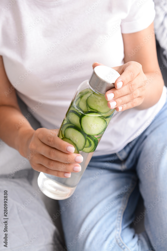 Woman with bottle of infused water at home