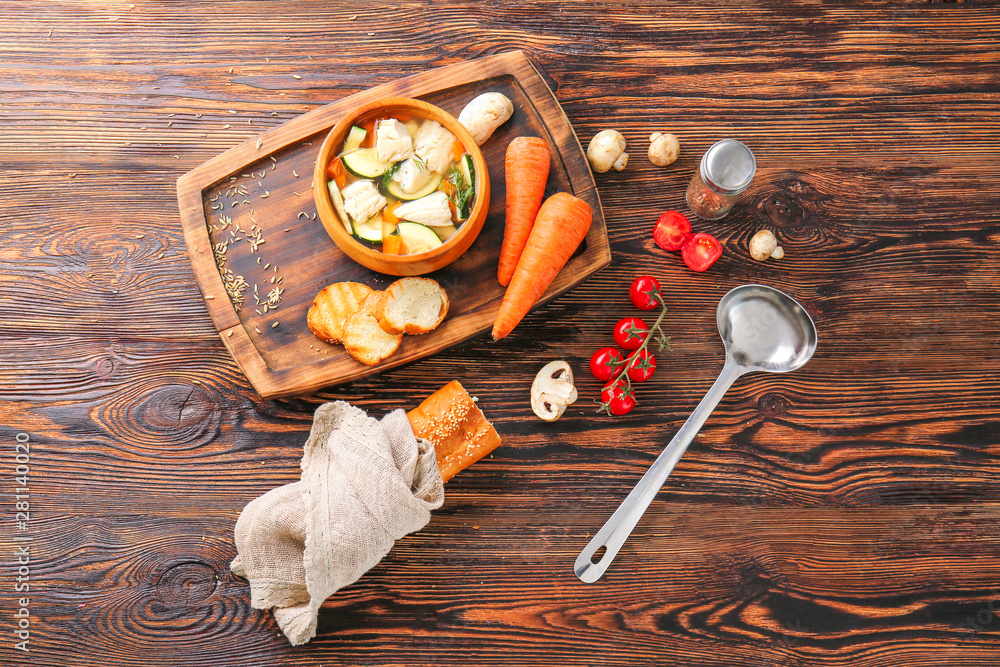 Bowl of tasty soup with vegetables and bread on wooden table