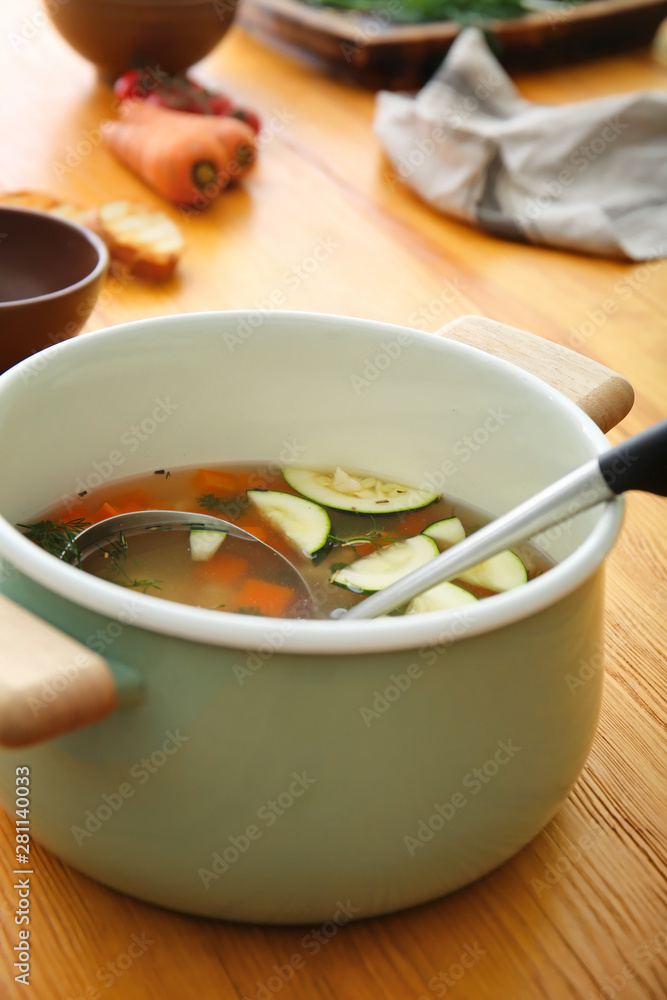 Pot of tasty soup on wooden table