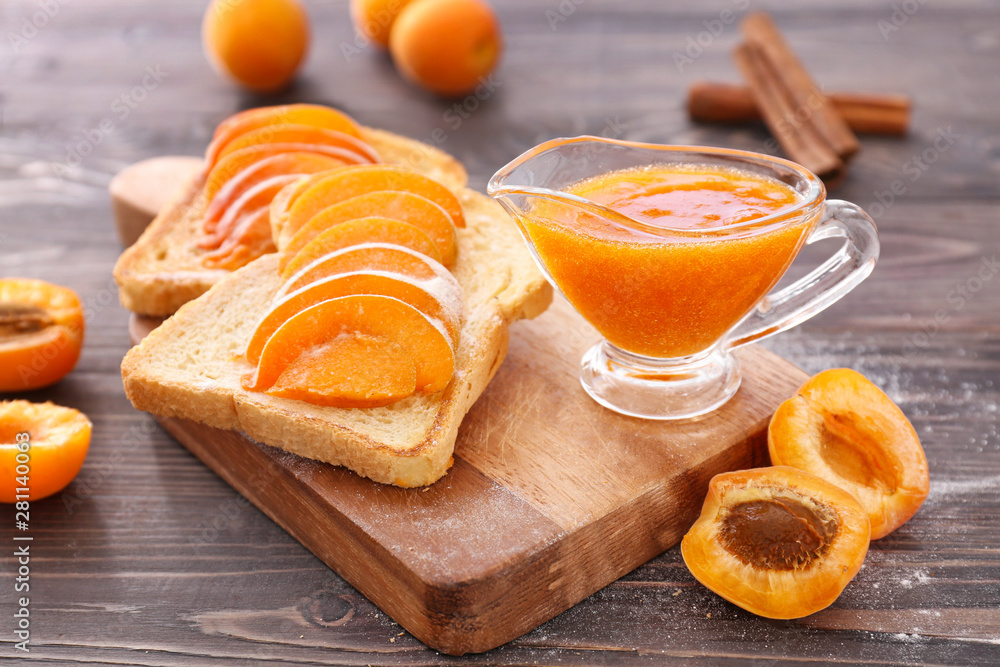 Bread slices with tasty apricot jam on wooden board