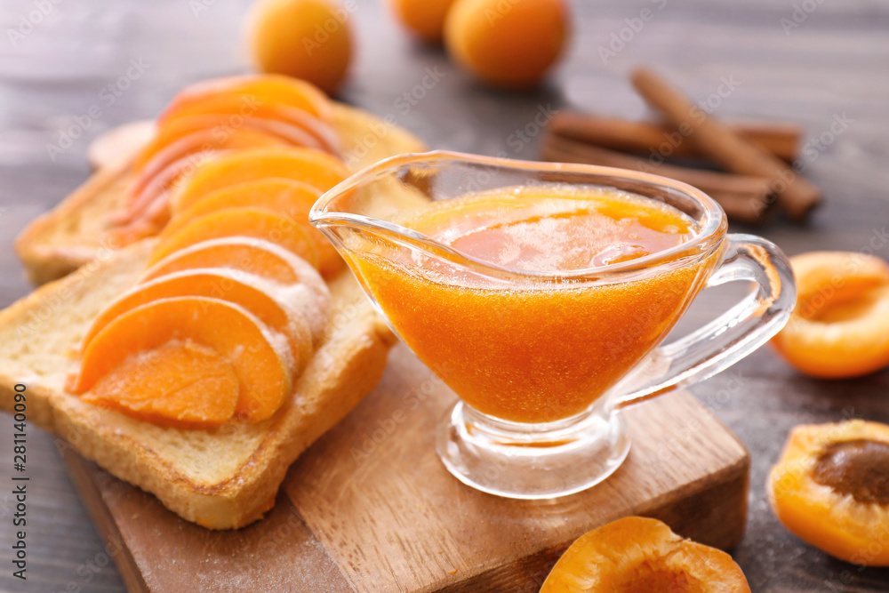 Bread slices with tasty apricot jam on wooden board