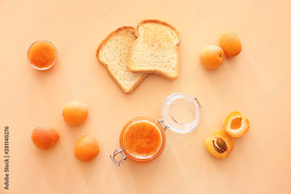 Tasty apricot jam with bread slices on color background