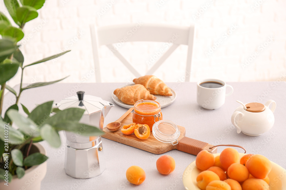 Tasty apricot jam with croissants and coffee on table