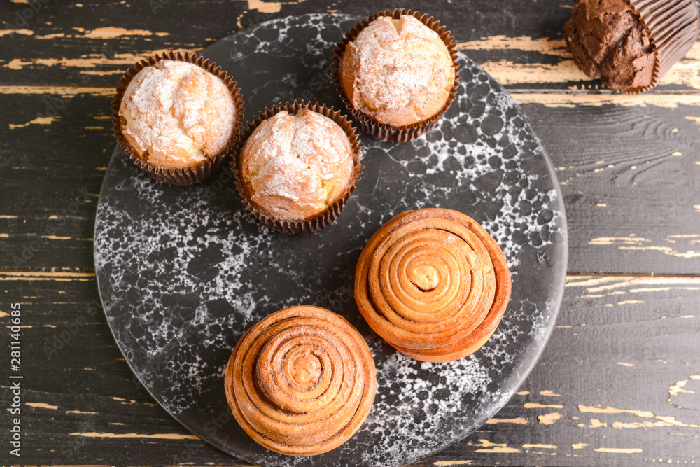 Tasty muffins with buns on wooden table