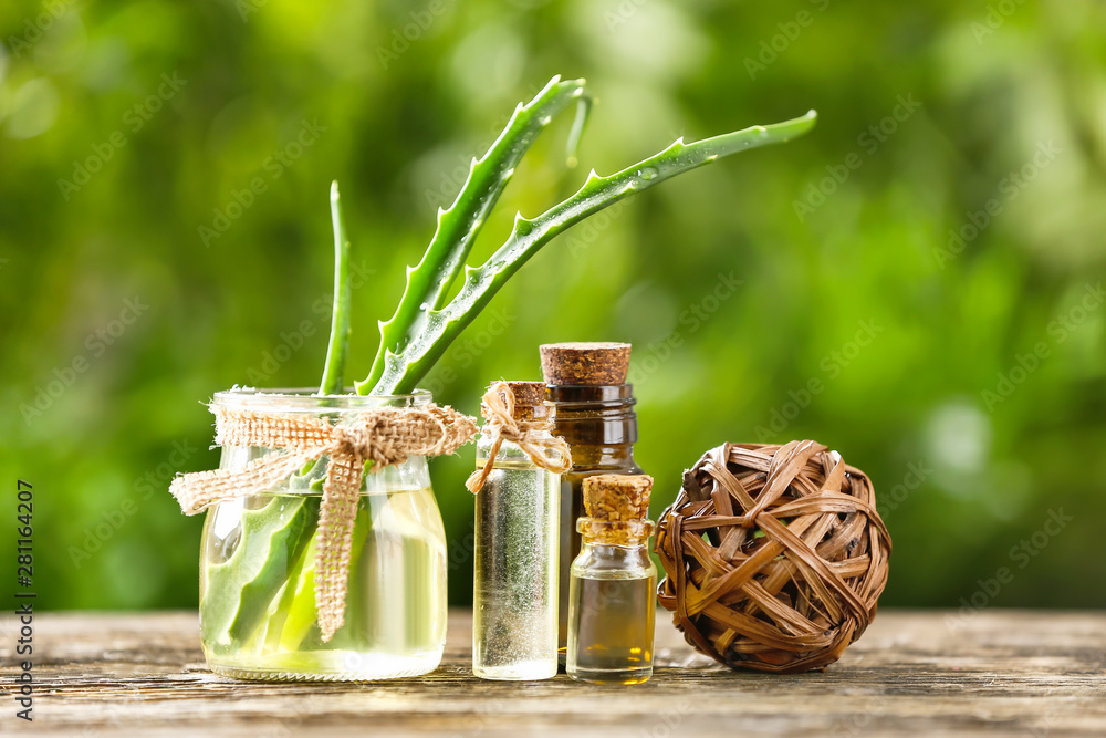 Bottles of aloe essential oil on wooden table