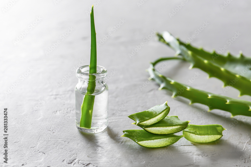 Slices of fresh aloe with essential oil on light background