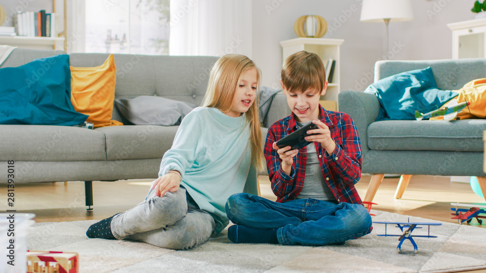 At Home: Cute Little Girl and Sweet Boy Playing Video Game on a Smartphone, Boy Holds Mobile Phone i