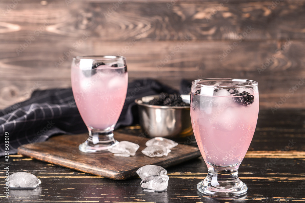 Glasses of tasty blackberry lemonade on dark wooden table