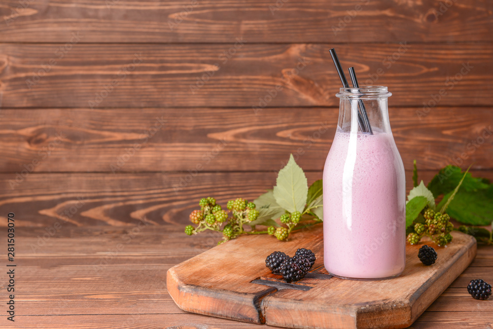 Bottle of tasty blackberry smoothie on wooden table