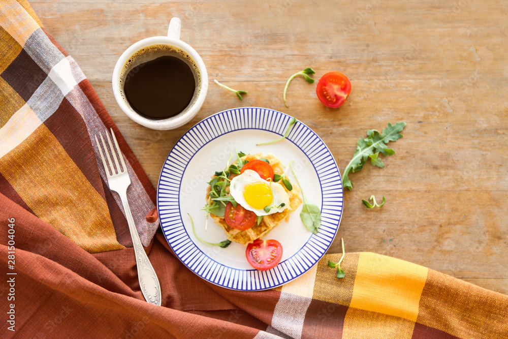 Plate with tasty waffles, fried egg and coffee on wooden table