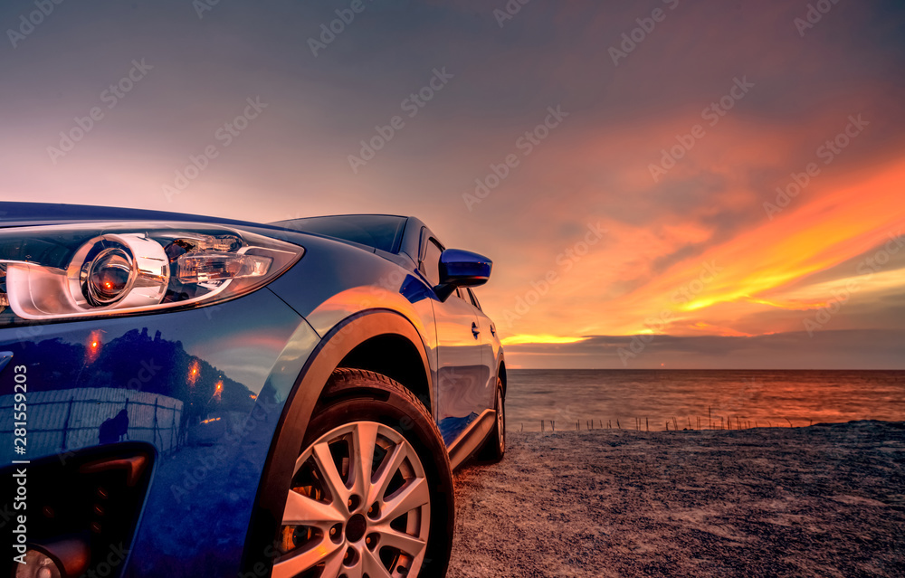 Blue compact SUV car with sport and modern design parked by beach at sunset. Hybrid and electric car