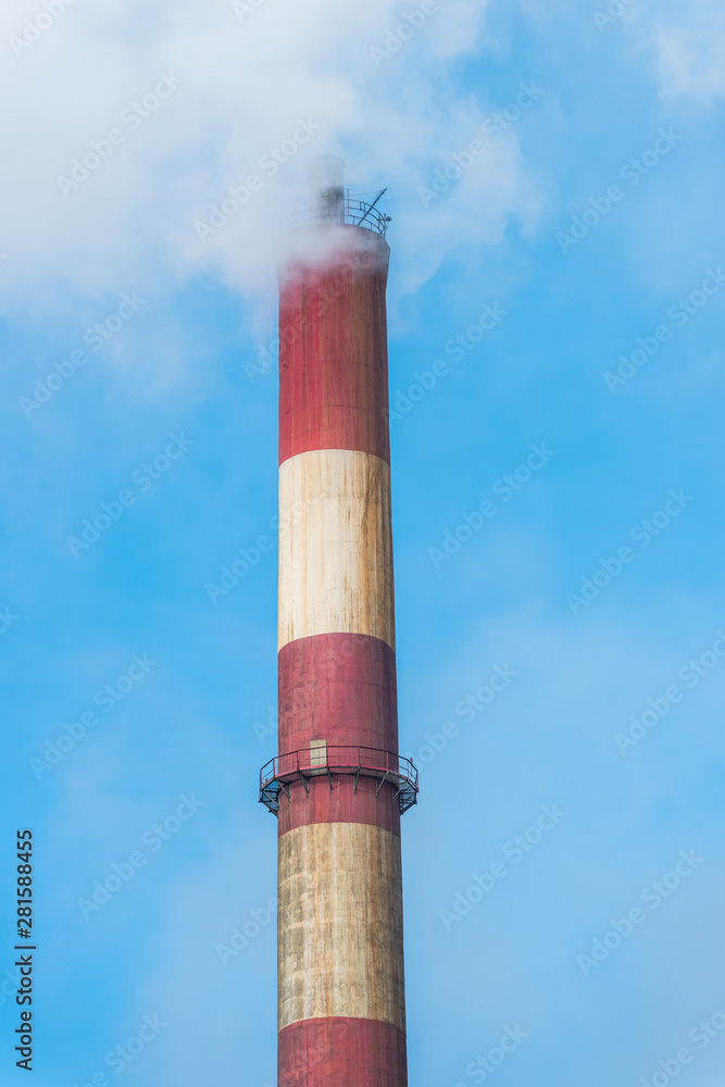 Smoky factory chimney on a background of blue sky.