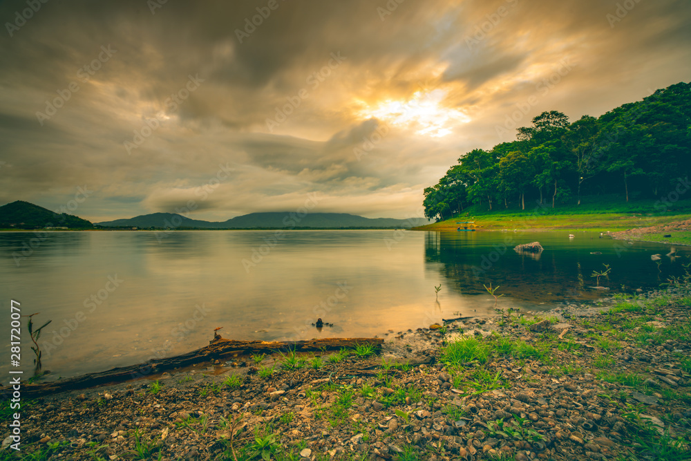 Beautiful landscape of Bang Pra reservoir in the morning with sunrise above the mountain and green t