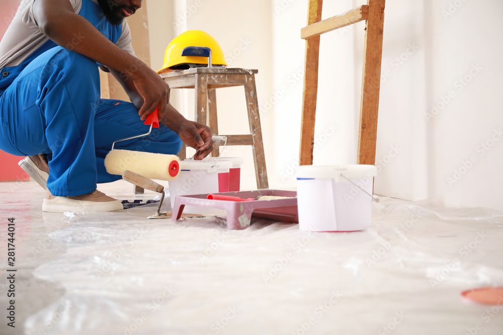 Male African-American decorator doing repair in room