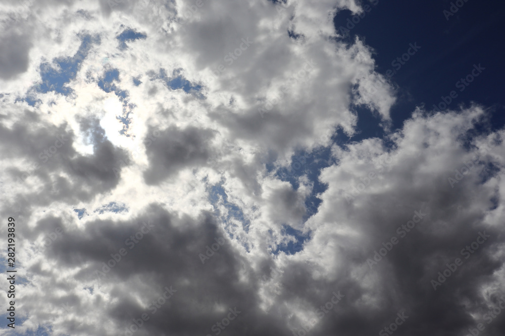 Sunbeams behind dark clouds on the blue sky background