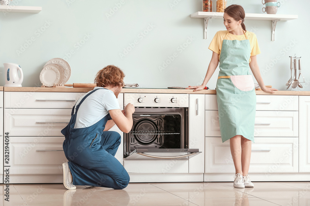 Worker repairing oven in kitchen