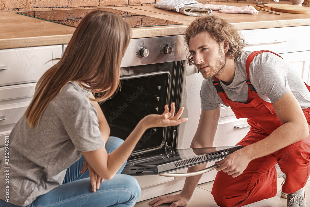 Worker repairing oven in kitchen