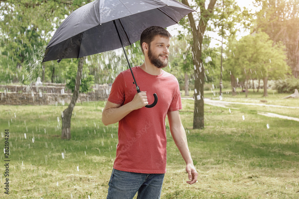 Handsome man with umbrella outdoors