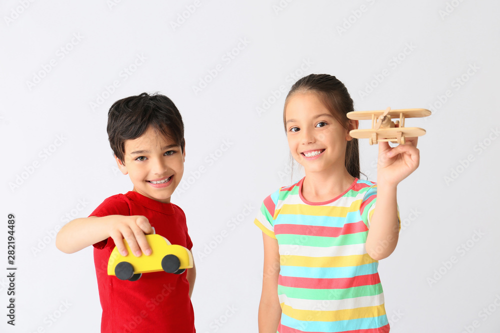 Cute little children with toys on light background