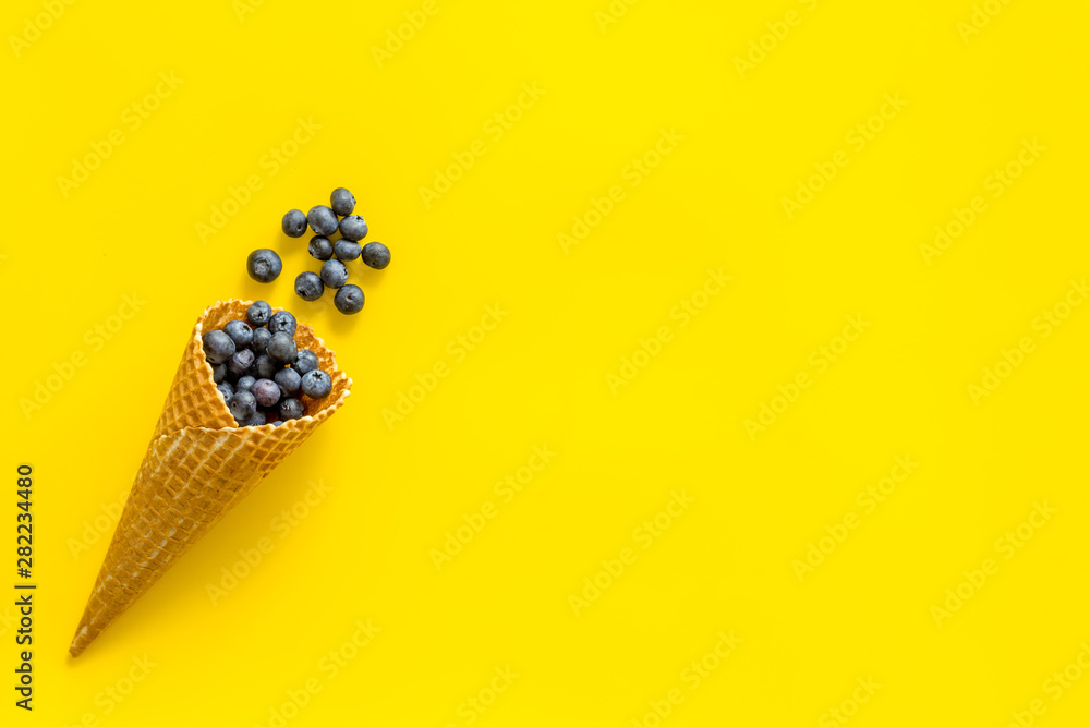 Fresh berries in waffle cones on yellow background top view mock up