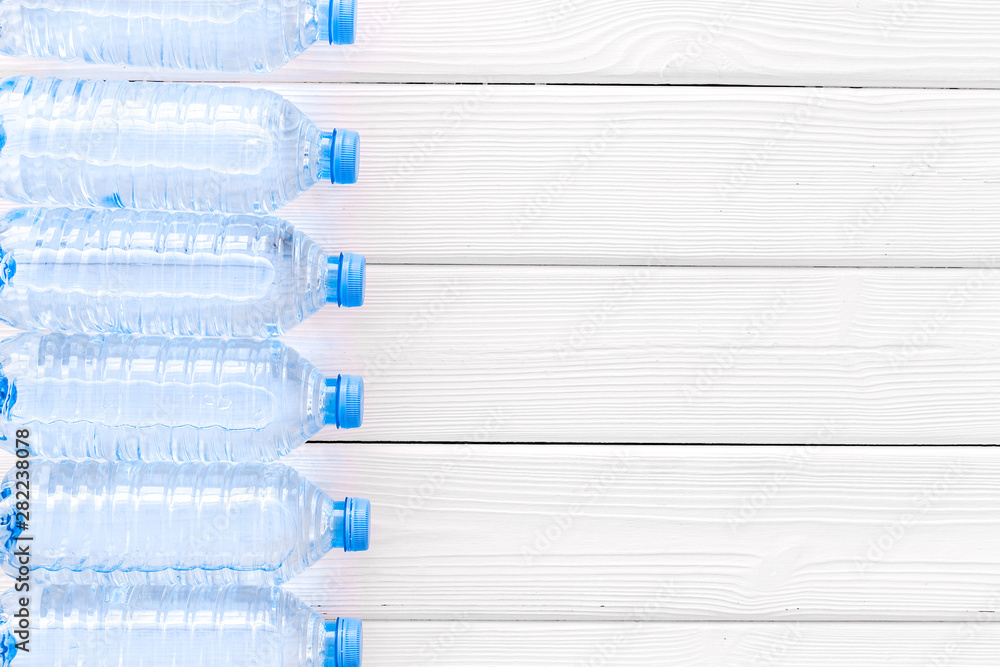 Pure water in plastic bottles on white wooden background top view copyspace