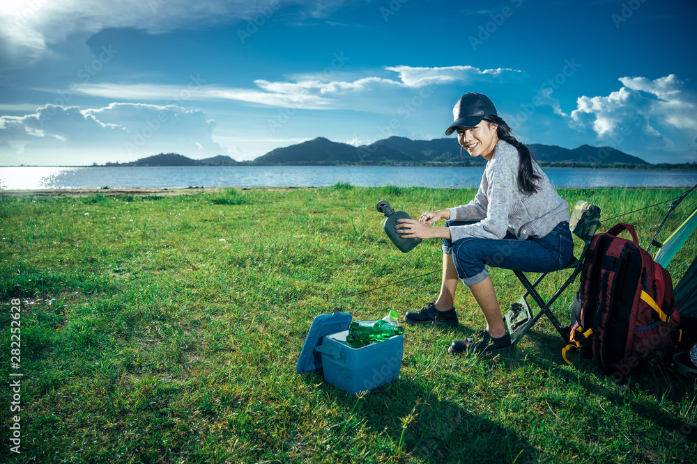 周末，亚洲年轻女性正在露营，并沿着道路走进森林，旅行放松