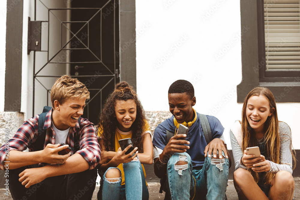 Friends sitting outdoors holding cell phones