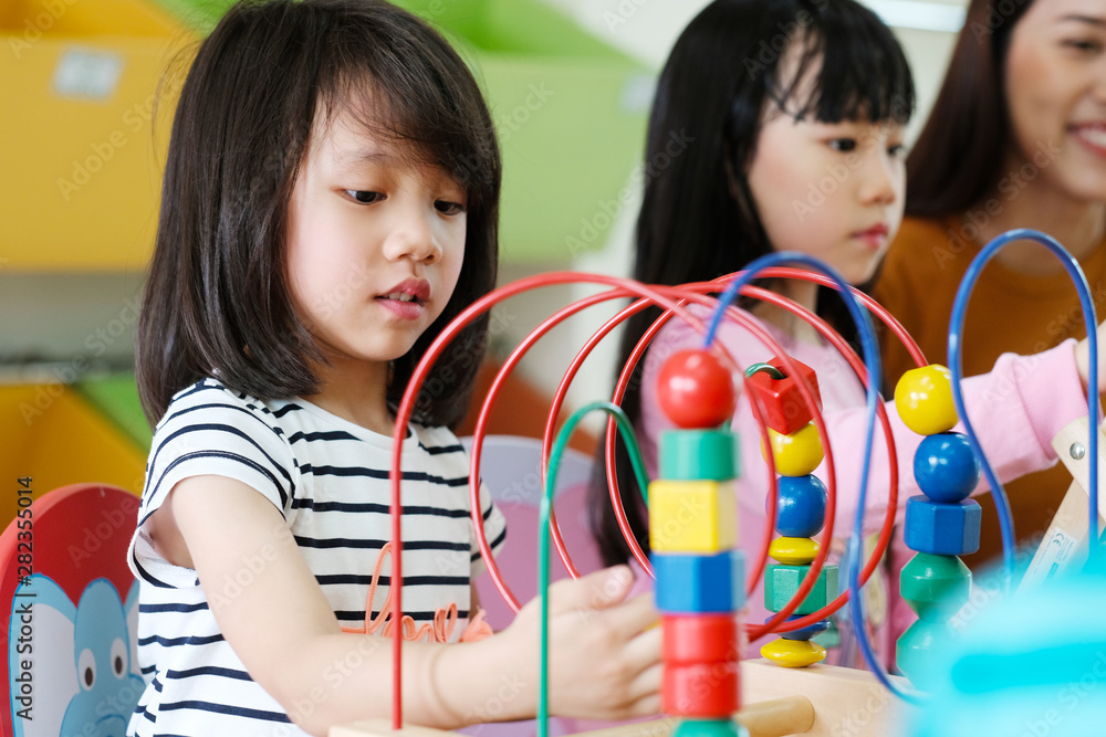 可爱的亚洲女孩在幼儿园教室里玩玩具，亚洲小学，学龄前儿童和老师