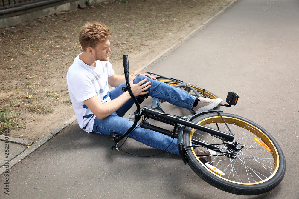 Young man fallen off his bicycle outdoors