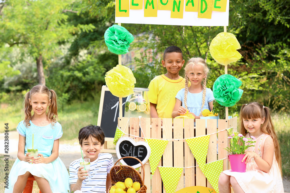 Cute little children selling lemonade in park