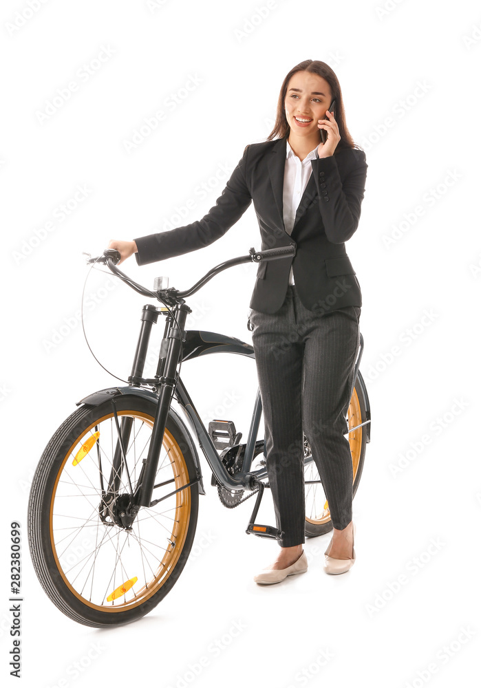 Young businesswoman with bicycle talking by phone against white background