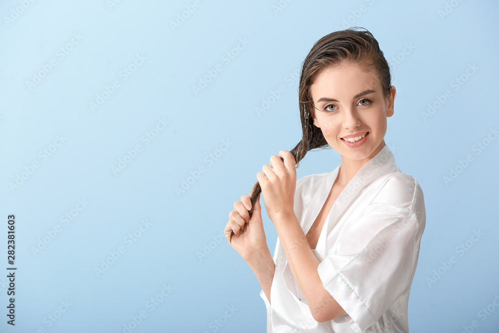 Beautiful young woman after washing hair against color background