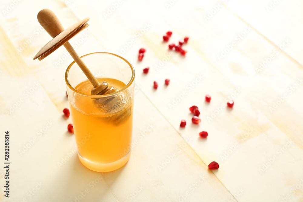 Glass with sweet honey on white wooden background