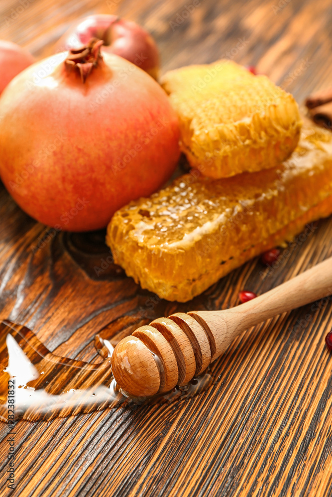 Honey dipper, pomegranate and combs on wooden background