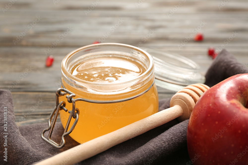 Jar of tasty honey, apple and dipper on table, closeup