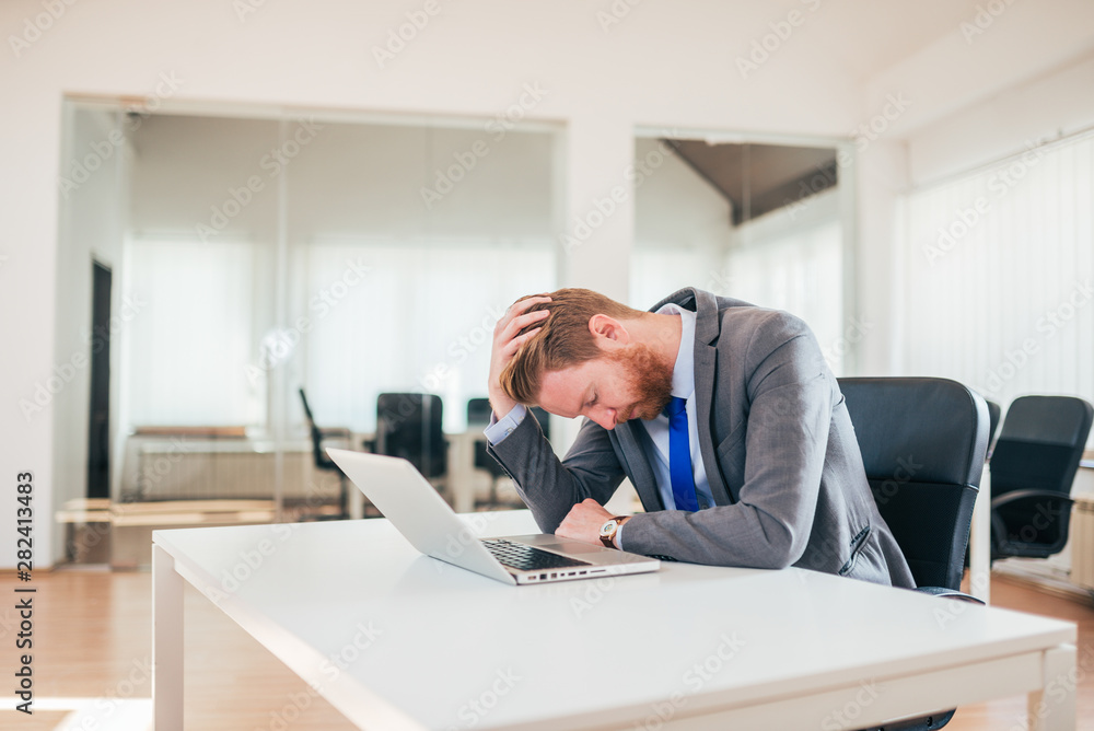 Overworked businessman sitting at office desk.