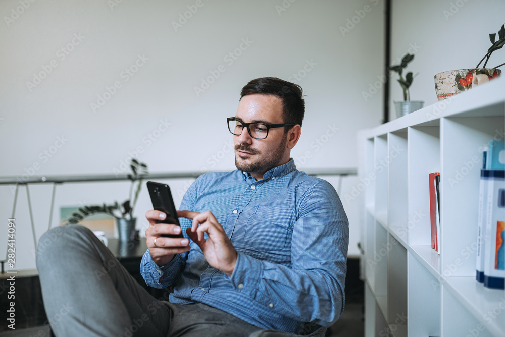 一名男子坐在椅子上使用手机。