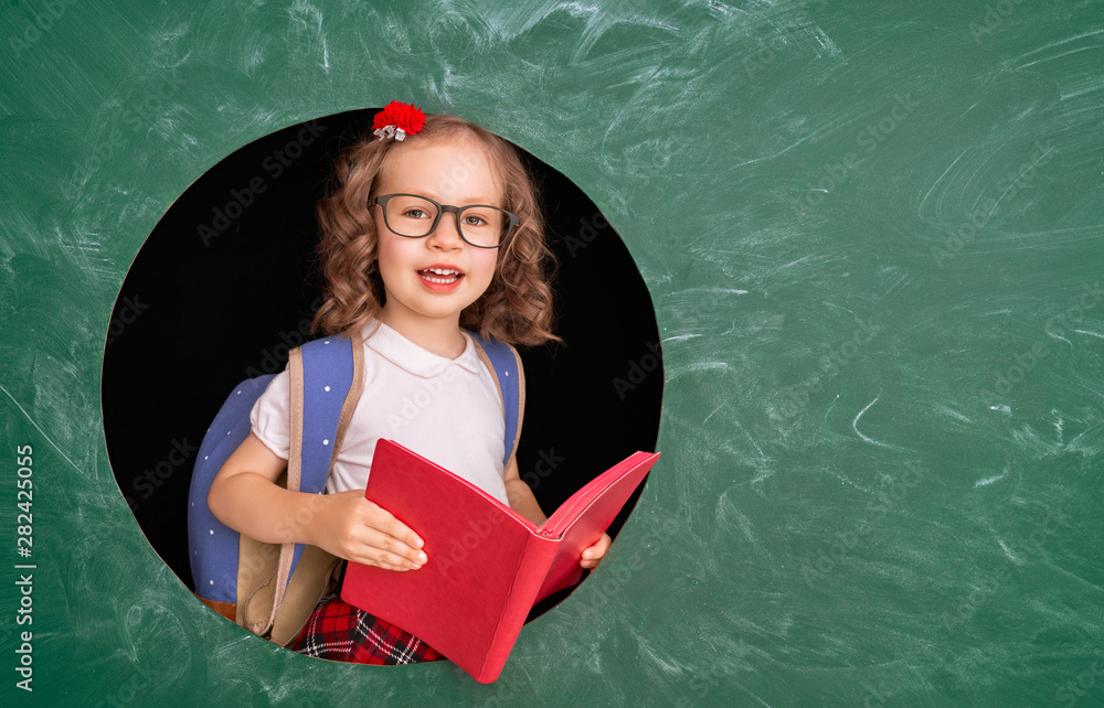 Kid in class on background of blackboard.