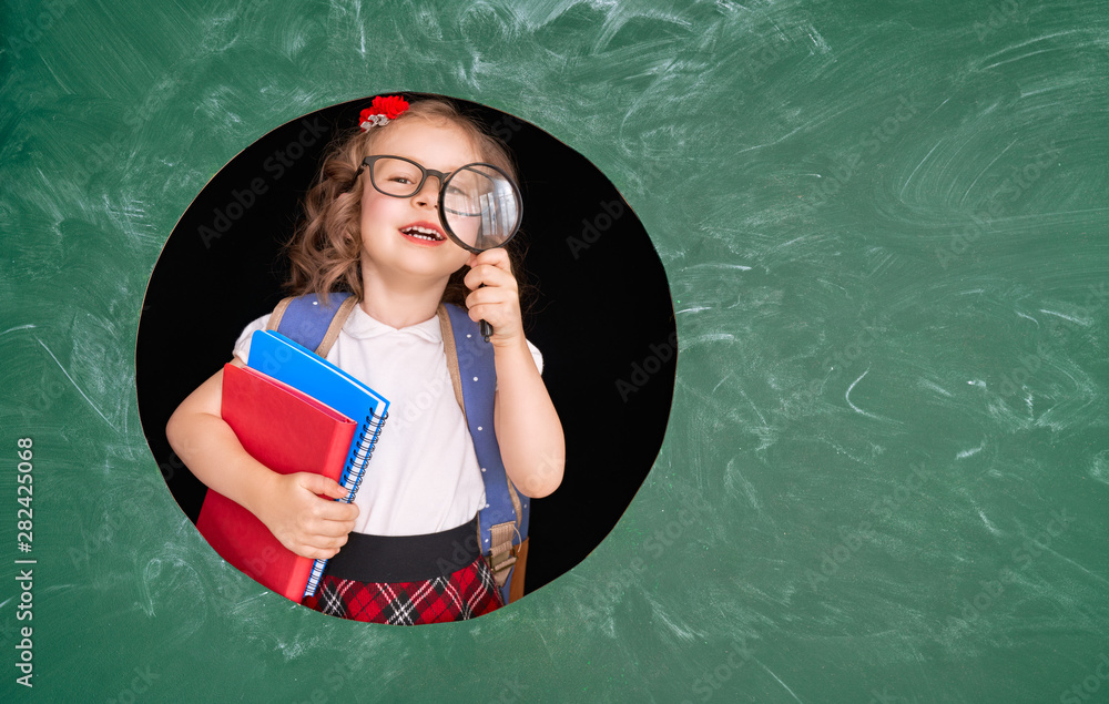 Kid in class on background of blackboard.